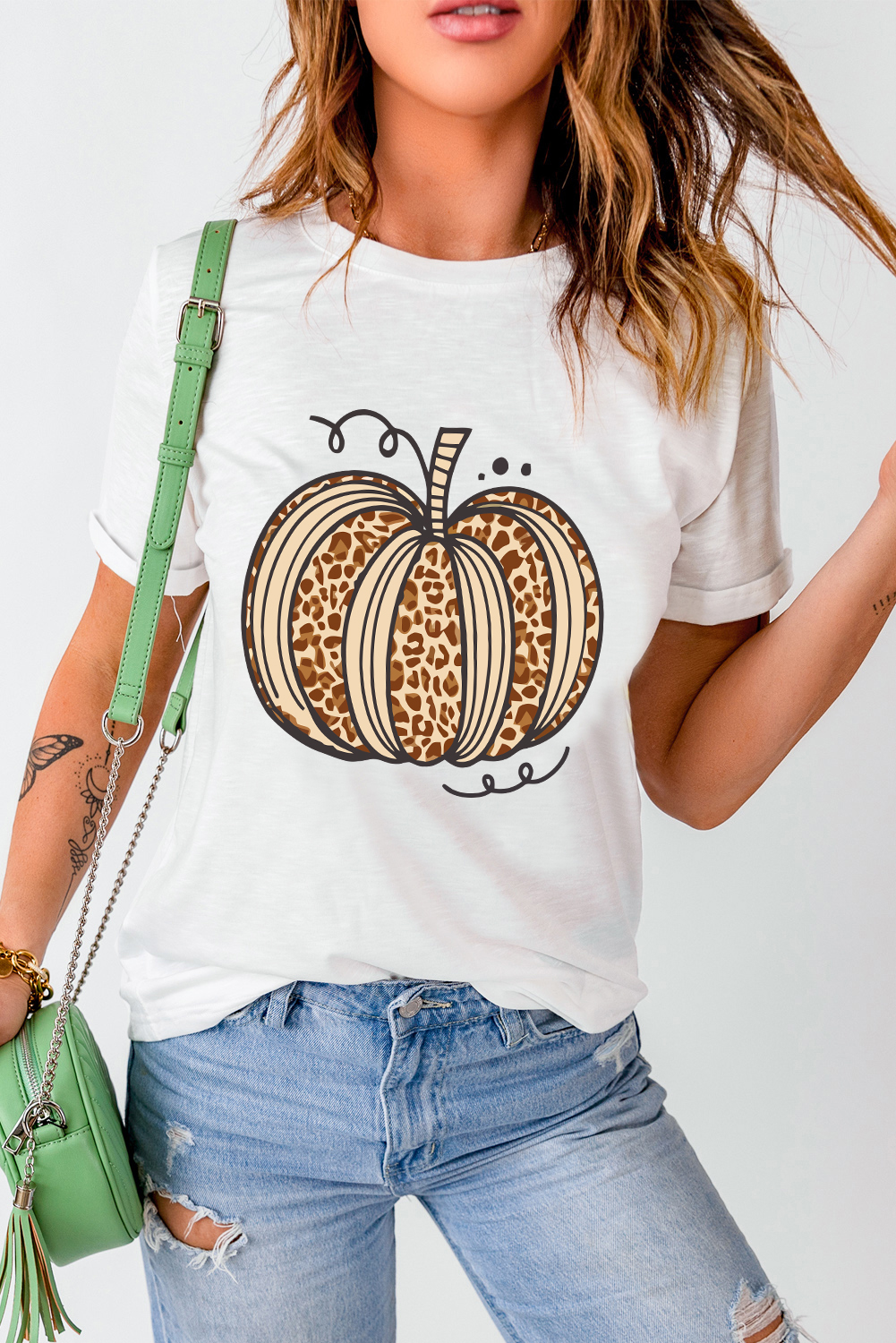 Embrace the essence of Halloween with this stylish Women's White Leopard Pumpkin Graphic Crewneck T-Shirt. Stand out with the festive pumpkin graphic, adding a touch of fun and charm to your look. The classic crew neck design ensures a comfortable fit, making it perfect for casual wear during the summer season. Made from a premium blend of 62% polyester, 32% cotton, and 6% elastane, this t-shirt offers a soft and breathable feel for all-day comfort. The white color with leopard print details adds a trendy and fashionable element to the design. Pair it with your favorite shorts or jeans for a laid-back and casual ensemble. This graphic tee features delicate cuttings and comes at attractive prices, making it a must-have addition to your wardrobe. - Detail View 4 Embrace the essence of Halloween with this stylish Women's White Leopard Pumpkin Graphic Crewneck T-Shirt. Stand out with the festive pumpkin graphic, adding a touch of fun and charm to your look. The classic crew neck design ensures a comfortable fit, making it perfect for casual wear during the summer season. Made from a premium blend of 62% polyester, 32% cotton, and 6% elastane, this t-shirt offers a soft and breathable feel for all-day comfort. The white color with leopard print details adds a trendy and fashionable element to the design. Pair it with your favorite shorts or jeans for a laid-back and casual ensemble. This graphic tee features delicate cuttings and comes at attractive prices, making it a must-have addition to your wardrobe. - Detail View 4