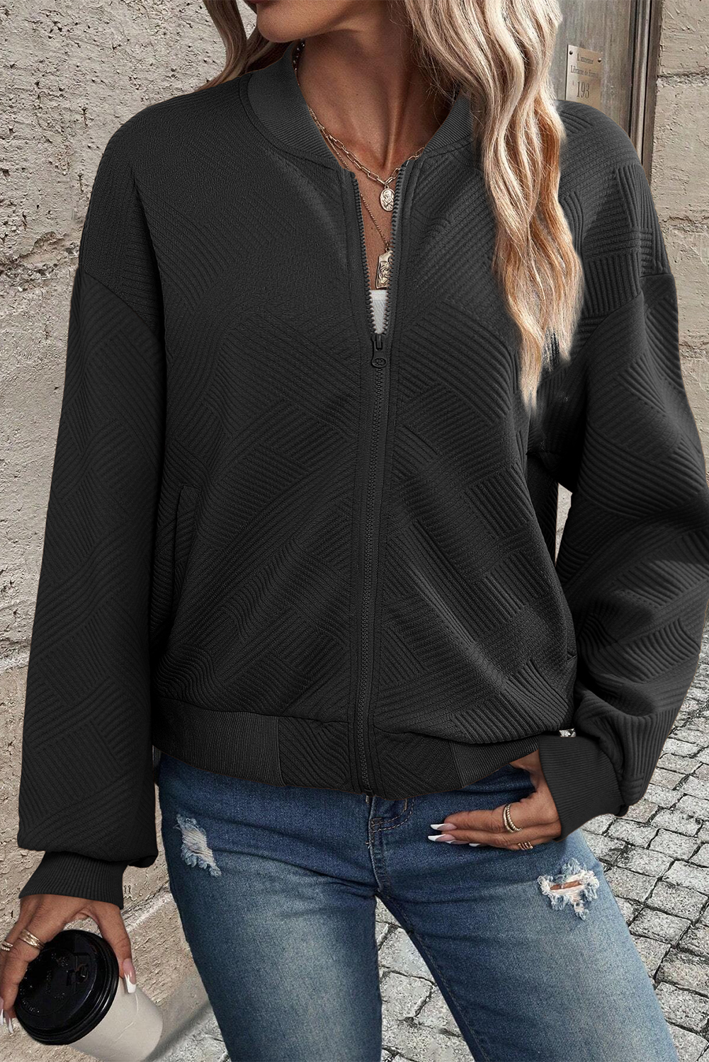 Stay warm and stylish with the Women's Black Solid Textured Stand Neck Zipper Bomber Jacket. Made from a soft yet durable textured fabric, this jacket provides a comfortable fit and easy movement. The sleek stand neckline and zipper closure elevate the overall look, making it perfect for both casual and dressy occasions. With a solid black color, this jacket is versatile and easy to style with your favorite outfit. Whether you're running errands or meeting up with friends, this bomber jacket is a must-have addition to your wardrobe, offering both fashion and functionality. - Detail View 4 Stay warm and stylish with the Women's Black Solid Textured Stand Neck Zipper Bomber Jacket. Made from a soft yet durable textured fabric, this jacket provides a comfortable fit and easy movement. The sleek stand neckline and zipper closure elevate the overall look, making it perfect for both casual and dressy occasions. With a solid black color, this jacket is versatile and easy to style with your favorite outfit. Whether you're running errands or meeting up with friends, this bomber jacket is a must-have addition to your wardrobe, offering both fashion and functionality. - Detail View 4