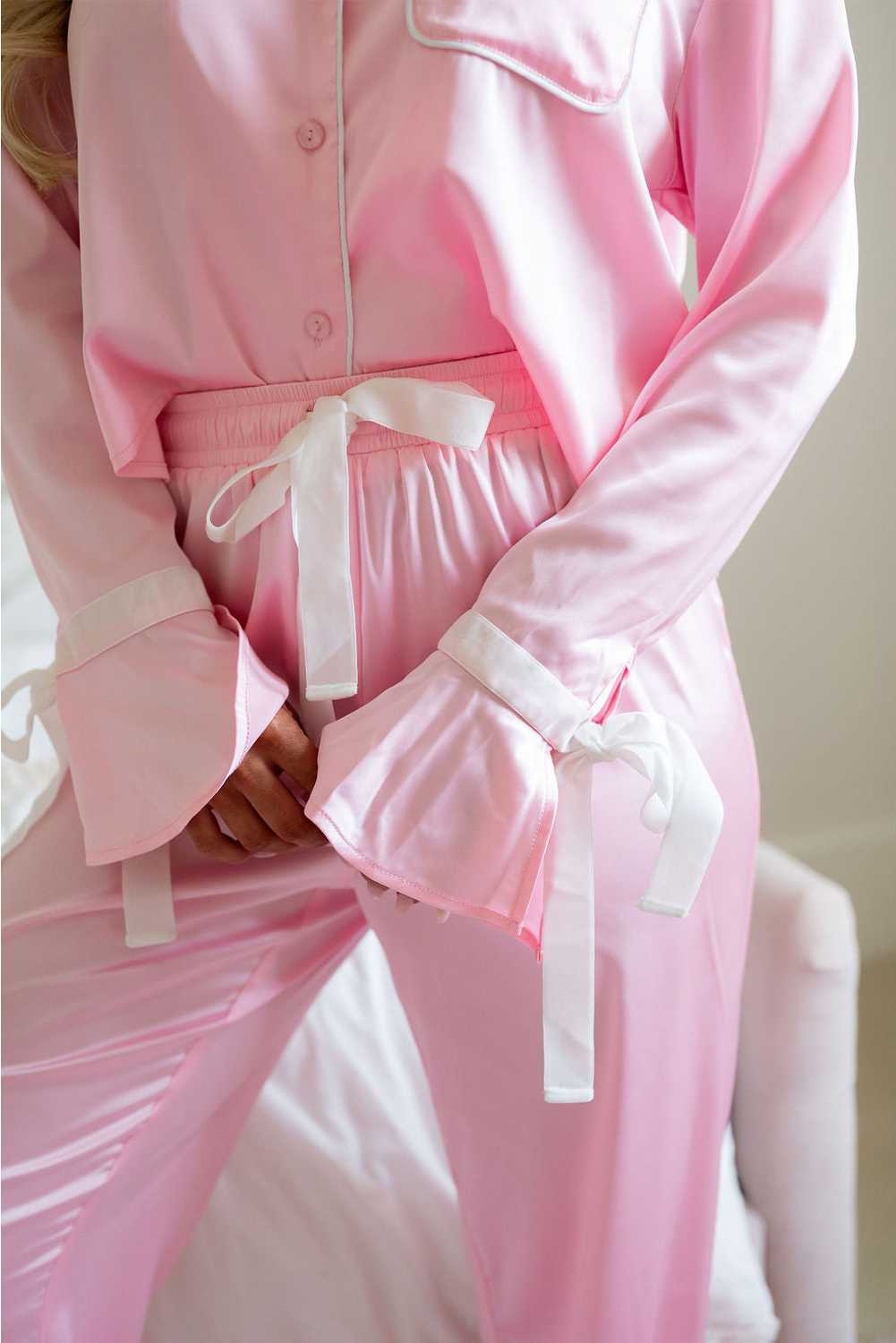 Indulge in luxury and comfort with this Women's Light Pink Satin Knot Accent Shirt and Ruffled Pants Lounge Set. This two-piece set brings a touch of luxury to relaxation, perfect for winding down after a long day. The satin knot accent on the pants adds a chic and stylish detail, while the ruffled pants provide a feminine silhouette, ideal for at-home comfort. Made from soft satin material, this lounge set ensures a cozy and comfortable feel, making it great for those seeking comfort and style in their downtime. The light pink color adds a delicate and elegant touch to the set, perfect for the fall and autumn season. Whether you're lounging at home or getting ready for a restful night's sleep, this elegant sleepwear set is a must-have addition to your wardrobe. - Detail View 9 Indulge in luxury and comfort with this Women's Light Pink Satin Knot Accent Shirt and Ruffled Pants Lounge Set. This two-piece set brings a touch of luxury to relaxation, perfect for winding down after a long day. The satin knot accent on the pants adds a chic and stylish detail, while the ruffled pants provide a feminine silhouette, ideal for at-home comfort. Made from soft satin material, this lounge set ensures a cozy and comfortable feel, making it great for those seeking comfort and style in their downtime. The light pink color adds a delicate and elegant touch to the set, perfect for the fall and autumn season. Whether you're lounging at home or getting ready for a restful night's sleep, this elegant sleepwear set is a must-have addition to your wardrobe. - Detail View 9