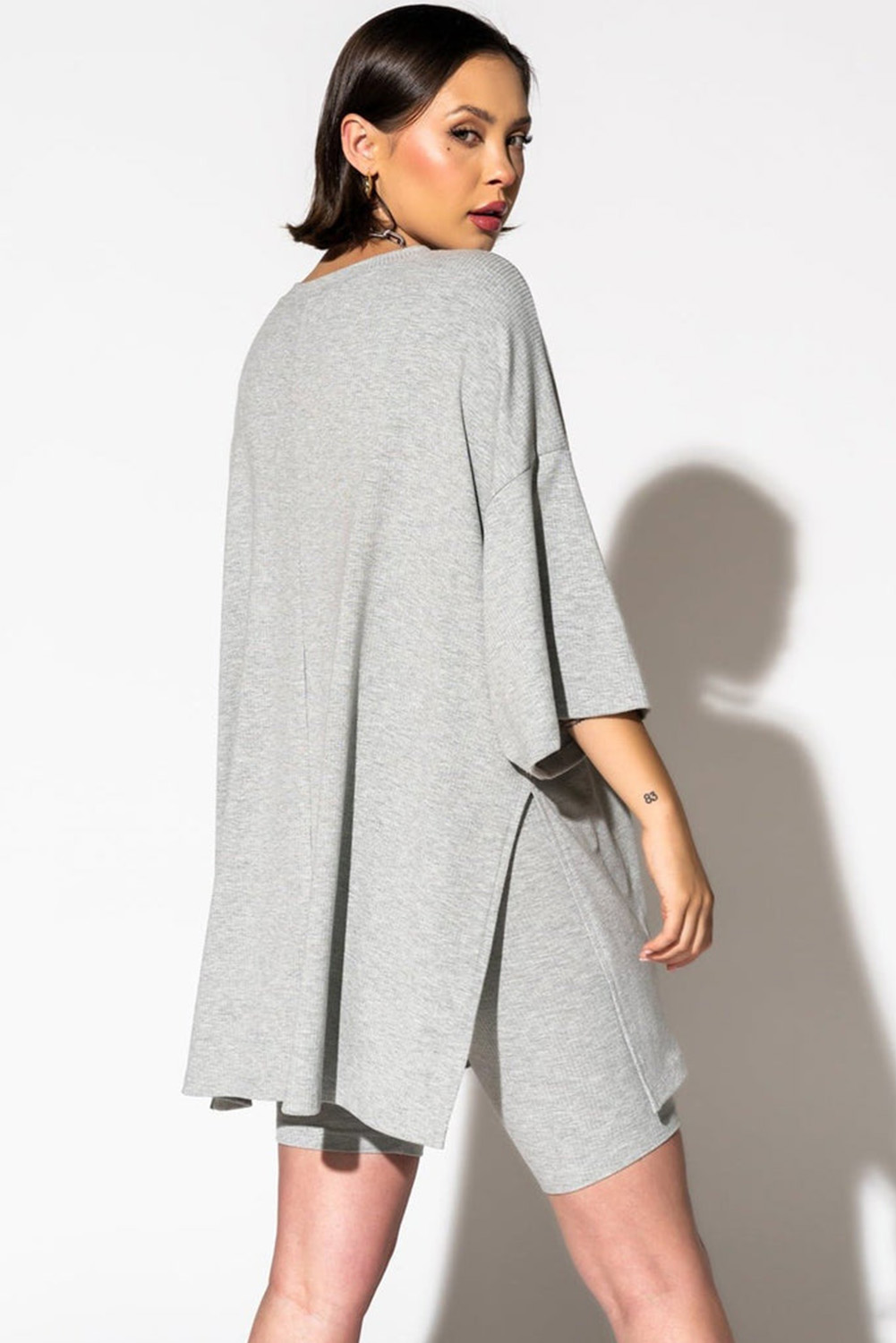 Elevate your casual wardrobe with this Women's Light Grey Solid Color Loose Tunic Top and Slim Shorts Set. The solid lounge set provides a versatile and chic ensemble, perfect for daily wear and casual outings. The loose tunic top offers a comfortable and relaxed fit, while the side slits add a touch of flair and movement, making it a stylish choice. The high-waisted slim shorts complete the two-piece set for a coordinated outfit, adding a trendy and fashionable element. Made from a premium blend of 93% viscose and 7% elastane, this set ensures a comfortable and breathable wear. The light grey color is timeless and easy to mix and match with other pieces in your wardrobe. This best-selling two-piece set is a must-have addition to your summer collection, offering both style and comfort. - Detail View 4 Elevate your casual wardrobe with this Women's Light Grey Solid Color Loose Tunic Top and Slim Shorts Set. The solid lounge set provides a versatile and chic ensemble, perfect for daily wear and casual outings. The loose tunic top offers a comfortable and relaxed fit, while the side slits add a touch of flair and movement, making it a stylish choice. The high-waisted slim shorts complete the two-piece set for a coordinated outfit, adding a trendy and fashionable element. Made from a premium blend of 93% viscose and 7% elastane, this set ensures a comfortable and breathable wear. The light grey color is timeless and easy to mix and match with other pieces in your wardrobe. This best-selling two-piece set is a must-have addition to your summer collection, offering both style and comfort. - Detail View 4