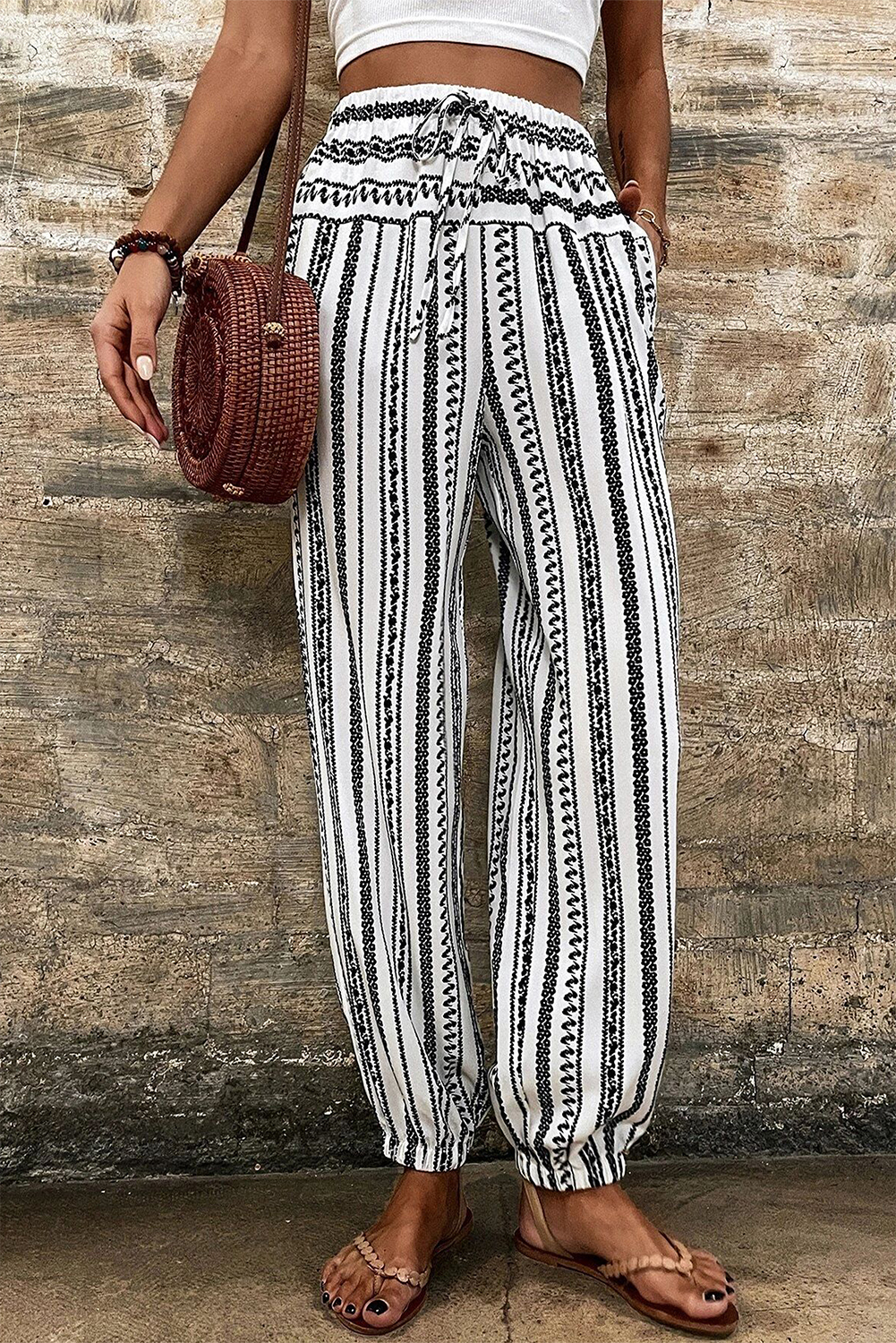 Make a statement with these Women's Black Stripe Boho Striped Print Casual Pants. The printed joggers create a trendy and eclectic look, perfect for adding a touch of bohemian style to your daily outfit. The wide leg design provides a comfortable and relaxed fit, while the high waist style creates a flattering and on-trend silhouette. The drawstring closure ensures adjustable comfort and style, making it easy to customize the fit to your liking. Whether you're heading to a casual brunch or relaxing on a beach vacation, these pants are sure to update your wardrobe with their versatile and chic design. Made from soft 100% polyester, these pants are easy to care for and maintain their texture and pattern. Pair them with a graphic tee and sneakers for a relaxed look, or dress them up with a blouse and sandals for a more polished ensemble. With various styles to choose from, you're sure to find the perfect pair to match your unique sense of style. - Detail View 4 Make a statement with these Women's Black Stripe Boho Striped Print Casual Pants. The printed joggers create a trendy and eclectic look, perfect for adding a touch of bohemian style to your daily outfit. The wide leg design provides a comfortable and relaxed fit, while the high waist style creates a flattering and on-trend silhouette. The drawstring closure ensures adjustable comfort and style, making it easy to customize the fit to your liking. Whether you're heading to a casual brunch or relaxing on a beach vacation, these pants are sure to update your wardrobe with their versatile and chic design. Made from soft 100% polyester, these pants are easy to care for and maintain their texture and pattern. Pair them with a graphic tee and sneakers for a relaxed look, or dress them up with a blouse and sandals for a more polished ensemble. With various styles to choose from, you're sure to find the perfect pair to match your unique sense of style. - Detail View 4