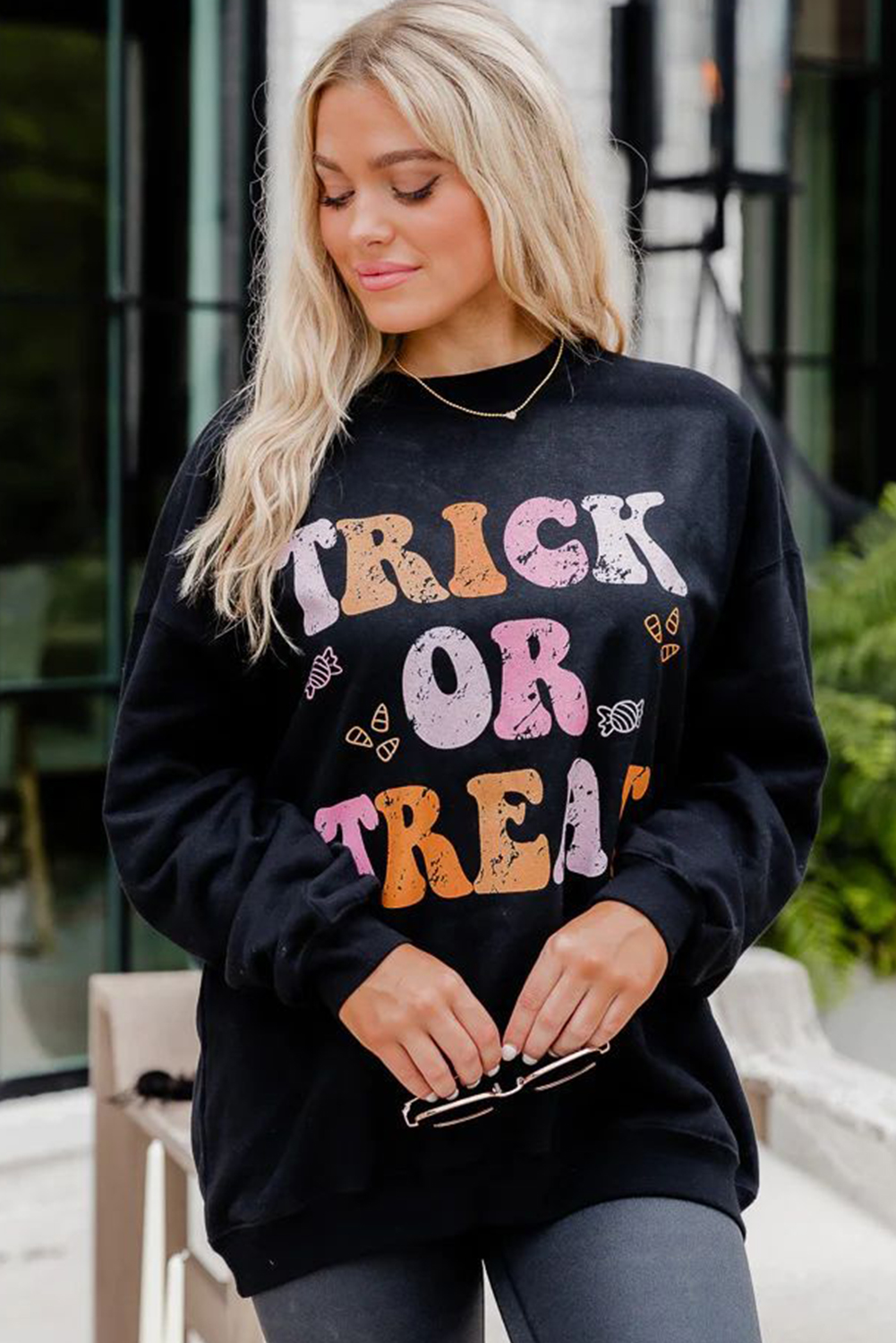 Embrace the Halloween spirit with this Women's Black TRICK OR TREAT Graphic Crewneck Halloween Sweatshirt. The cozy and festive sweatshirt is the perfect option for the Halloween season, offering a classic and comfortable style with its crewneck design and baggy fit. The playful TRICK OR TREAT graphic captures the essence of Halloween, adding a fun and spirited touch to your outfit. Made from a blend of 50% polyester and 50% cotton, this sweatshirt ensures both comfort and durability. Pair it with costume bottoms or casual jeans for a complete Halloween look, whether you're out trick-or-treating or attending festive gatherings. The long sleeves and round neck provide additional warmth for outdoor festivities, keeping you cozy and stylish throughout the season. - Detail View 4 Embrace the Halloween spirit with this Women's Black TRICK OR TREAT Graphic Crewneck Halloween Sweatshirt. The cozy and festive sweatshirt is the perfect option for the Halloween season, offering a classic and comfortable style with its crewneck design and baggy fit. The playful TRICK OR TREAT graphic captures the essence of Halloween, adding a fun and spirited touch to your outfit. Made from a blend of 50% polyester and 50% cotton, this sweatshirt ensures both comfort and durability. Pair it with costume bottoms or casual jeans for a complete Halloween look, whether you're out trick-or-treating or attending festive gatherings. The long sleeves and round neck provide additional warmth for outdoor festivities, keeping you cozy and stylish throughout the season. - Detail View 4