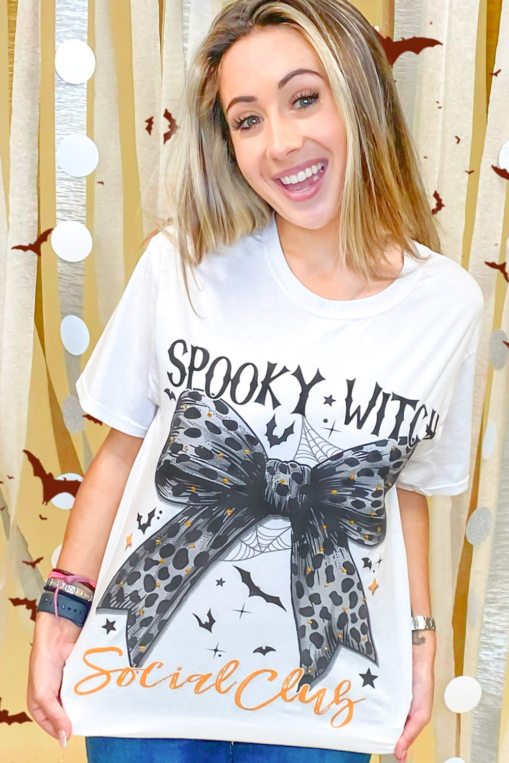Get into the spooky spirit with this Women's White Spooky Witch Leopard Bowknot Bat Graphic Halloween T-Shirt. A fun and festive choice for the Halloween season, this graphic tee features a playful leopard bowknot print and a bat graphic, adding a touch of Halloween flair to your outfit. The cozy blend of 62% polyester, 32% cotton, and 6% elastane ensures a comfortable wear for all your Halloween celebrations. Pair this tee with leggings or jeans for a casual, Halloween-ready outfit that is perfect for trick-or-treating or themed parties. The round neck and short sleeves make it a versatile and easy-to-wear option for daily wear and special Halloween events. Embrace the Halloween spirit with this stylish and fun graphic t-shirt! - Detail View 9 Get into the spooky spirit with this Women's White Spooky Witch Leopard Bowknot Bat Graphic Halloween T-Shirt. A fun and festive choice for the Halloween season, this graphic tee features a playful leopard bowknot print and a bat graphic, adding a touch of Halloween flair to your outfit. The cozy blend of 62% polyester, 32% cotton, and 6% elastane ensures a comfortable wear for all your Halloween celebrations. Pair this tee with leggings or jeans for a casual, Halloween-ready outfit that is perfect for trick-or-treating or themed parties. The round neck and short sleeves make it a versatile and easy-to-wear option for daily wear and special Halloween events. Embrace the Halloween spirit with this stylish and fun graphic t-shirt! - Detail View 9