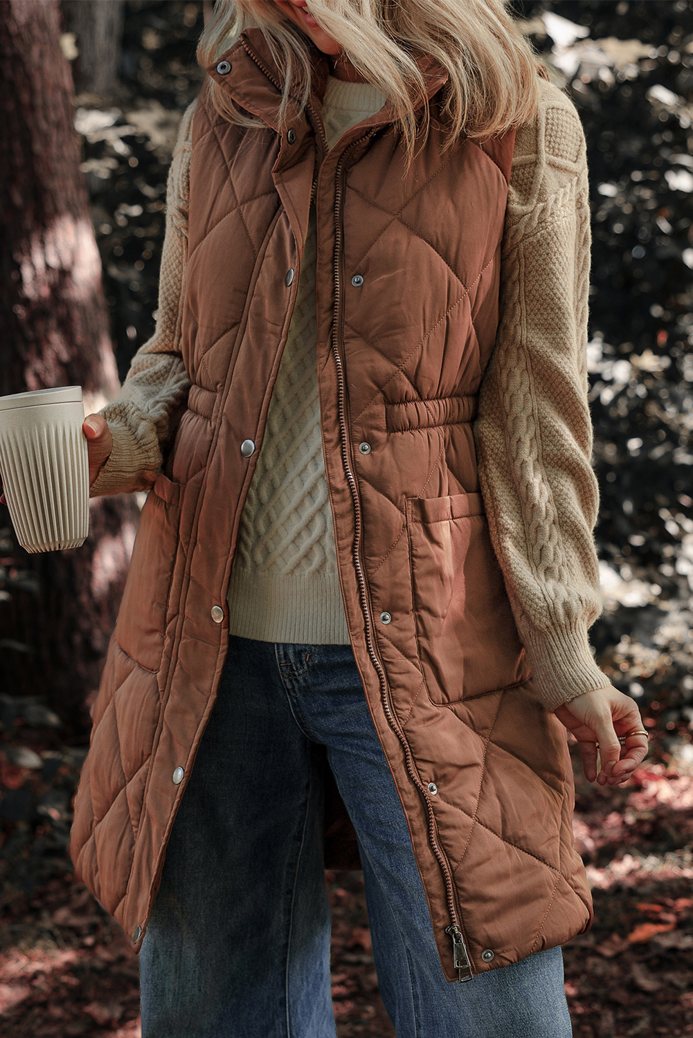 Stay warm and stylish with this Women's Coffee Quilted Longline Puffer Vest with Stand Collar. The longline coverage provides added warmth and a streamlined silhouette, while the fashionable quilted design adds a stylish texture and classic look. The stand-up collar provides extra neck protection and a sharp, chic appearance. This light and warm puffer construction is perfect for effortless layering in cold weather, making it a must-have for your winter wardrobe. The coffee brown color is versatile and easy to style, and can be paired with a variety of outfits for a chic and effortless look. - Detail View 4 Stay warm and stylish with this Women's Coffee Quilted Longline Puffer Vest with Stand Collar. The longline coverage provides added warmth and a streamlined silhouette, while the fashionable quilted design adds a stylish texture and classic look. The stand-up collar provides extra neck protection and a sharp, chic appearance. This light and warm puffer construction is perfect for effortless layering in cold weather, making it a must-have for your winter wardrobe. The coffee brown color is versatile and easy to style, and can be paired with a variety of outfits for a chic and effortless look. - Detail View 4