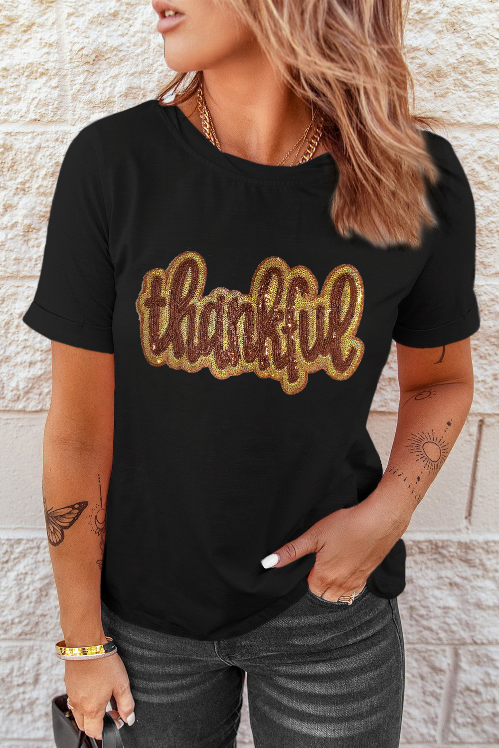 Bring warmth and style to your holiday outfit with this Women's Black Sequined Thankful Graphic Round Neck Tee. The shiny sequins on the Thankful graphic add a touch of elegance and meaning to this casual tee. The round neck and shift fit combine for a comfortable and relaxed fit, perfect for daily wear. The soft and breathable material ensures a cozy wear, making it ideal for layering. This graphic tee is a must-have for celebrating the holiday season, whether for Thanksgiving or any other special occasion. Pair it with jeans or leggings for a chic and effortless look. - Detail View 4 Bring warmth and style to your holiday outfit with this Women's Black Sequined Thankful Graphic Round Neck Tee. The shiny sequins on the Thankful graphic add a touch of elegance and meaning to this casual tee. The round neck and shift fit combine for a comfortable and relaxed fit, perfect for daily wear. The soft and breathable material ensures a cozy wear, making it ideal for layering. This graphic tee is a must-have for celebrating the holiday season, whether for Thanksgiving or any other special occasion. Pair it with jeans or leggings for a chic and effortless look. - Detail View 4