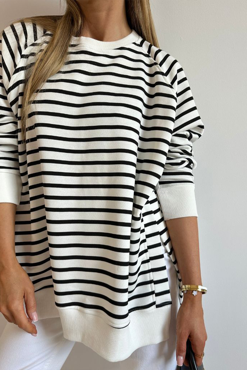 Elevate your casual wear with this Women's Black Stripe Raglan Sleeve Loose Fit Sweatshirt with Side Slits. The classic striped pattern is both timeless and trendy, featuring a chic crew neckline, raglan sleeves, and a loose fit style. The side slits add a modern and edgy touch, enhancing the sweatshirt's casual appeal. Perfect for everyday wear, this sweatshirt pairs well with casual jeans and sweatpants. Made from a soft and breathable blend of 95% cotton and 5% elastane, it offers both style and comfort. This sweatshirt is a great addition to your wardrobe, suitable for daily wear and offering a relaxed and stylish look. - Detail View 4 Elevate your casual wear with this Women's Black Stripe Raglan Sleeve Loose Fit Sweatshirt with Side Slits. The classic striped pattern is both timeless and trendy, featuring a chic crew neckline, raglan sleeves, and a loose fit style. The side slits add a modern and edgy touch, enhancing the sweatshirt's casual appeal. Perfect for everyday wear, this sweatshirt pairs well with casual jeans and sweatpants. Made from a soft and breathable blend of 95% cotton and 5% elastane, it offers both style and comfort. This sweatshirt is a great addition to your wardrobe, suitable for daily wear and offering a relaxed and stylish look. - Detail View 4