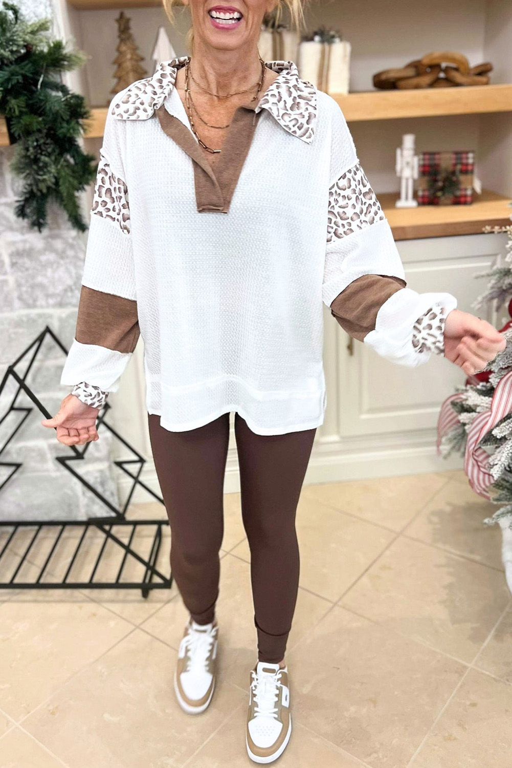 Elevate your casual style with this Women's White Leopard Patchwork Turn-down Collar Waffle Top. The chic and oversize fit of this top offers comfort and a trendy look for most body types. The leopard patchwork detail adds a touch of fashion-forward style, making it a statement piece in your wardrobe. The turn-down collar, oversize style, and tunic length give this top a modern and relaxed vibe. Featuring side slits for added detail, this pullover is perfect for the upcoming fall and autumn season. Made from premium 100% polyester, this top ensures durability and easy care. The long sleeves and V-neck collar are in line with the latest fashion trends, adding a touch of sophistication to the overall look. Pair it with your favorite jeans or leggings for a stylish and effortless ensemble. Embrace the best of fall fashion with this must-have waffle top. - Detail View 4 Elevate your casual style with this Women's White Leopard Patchwork Turn-down Collar Waffle Top. The chic and oversize fit of this top offers comfort and a trendy look for most body types. The leopard patchwork detail adds a touch of fashion-forward style, making it a statement piece in your wardrobe. The turn-down collar, oversize style, and tunic length give this top a modern and relaxed vibe. Featuring side slits for added detail, this pullover is perfect for the upcoming fall and autumn season. Made from premium 100% polyester, this top ensures durability and easy care. The long sleeves and V-neck collar are in line with the latest fashion trends, adding a touch of sophistication to the overall look. Pair it with your favorite jeans or leggings for a stylish and effortless ensemble. Embrace the best of fall fashion with this must-have waffle top. - Detail View 4