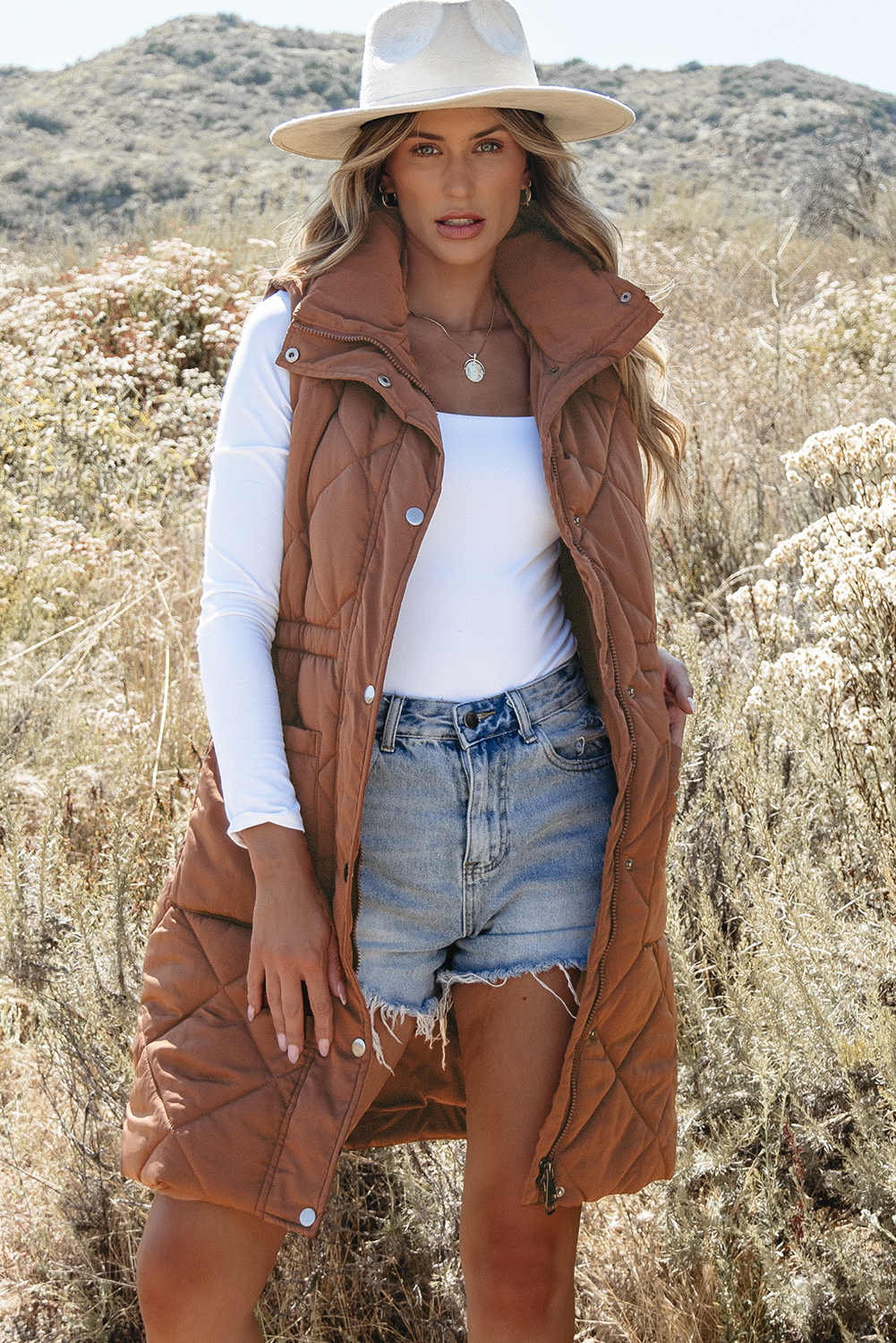 Stay warm and stylish with this Women's Coffee Quilted Longline Puffer Vest with Stand Collar. The longline coverage provides added warmth and a streamlined silhouette, while the fashionable quilted design adds a stylish texture and classic look. The stand-up collar provides extra neck protection and a sharp, chic appearance. This light and warm puffer construction is perfect for effortless layering in cold weather, making it a must-have for your winter wardrobe. The coffee brown color is versatile and easy to style, and can be paired with a variety of outfits for a chic and effortless look. - Detail View 14 Stay warm and stylish with this Women's Coffee Quilted Longline Puffer Vest with Stand Collar. The longline coverage provides added warmth and a streamlined silhouette, while the fashionable quilted design adds a stylish texture and classic look. The stand-up collar provides extra neck protection and a sharp, chic appearance. This light and warm puffer construction is perfect for effortless layering in cold weather, making it a must-have for your winter wardrobe. The coffee brown color is versatile and easy to style, and can be paired with a variety of outfits for a chic and effortless look. - Detail View 14