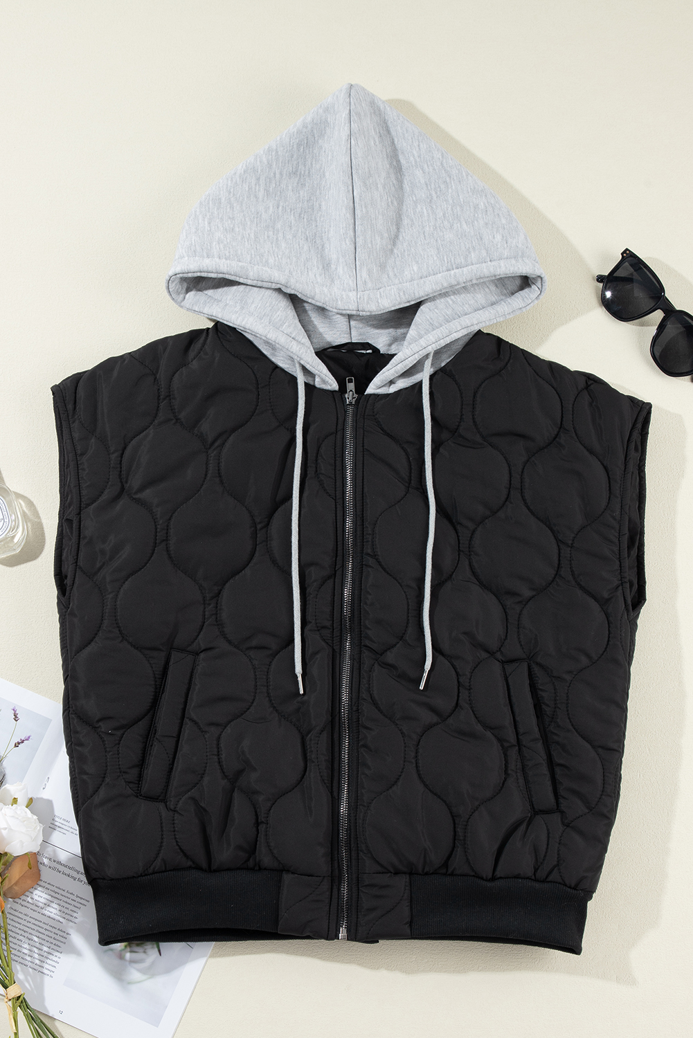 Stay cozy and stylish in the colder months with this Women's Black Quilted Hooded Zip-Up Puffer Vest. The premium quilted design adds a chic and fashionable look to the vest, while the convenient zip-up front ensures easy wear. The hooded design and drawstring provide extra warmth and style, making it a versatile and practical choice for the winter season. Made from 100% polyester, this vest offers both comfort and durability. The sleeveless silhouette allows for layering over your favorite long sleeve tops or sweaters. Perfect for daily wear and casual occasions, this black puffer vest is a must-have addition to your winter wardrobe. - Detail View 4 Stay cozy and stylish in the colder months with this Women's Black Quilted Hooded Zip-Up Puffer Vest. The premium quilted design adds a chic and fashionable look to the vest, while the convenient zip-up front ensures easy wear. The hooded design and drawstring provide extra warmth and style, making it a versatile and practical choice for the winter season. Made from 100% polyester, this vest offers both comfort and durability. The sleeveless silhouette allows for layering over your favorite long sleeve tops or sweaters. Perfect for daily wear and casual occasions, this black puffer vest is a must-have addition to your winter wardrobe. - Detail View 4