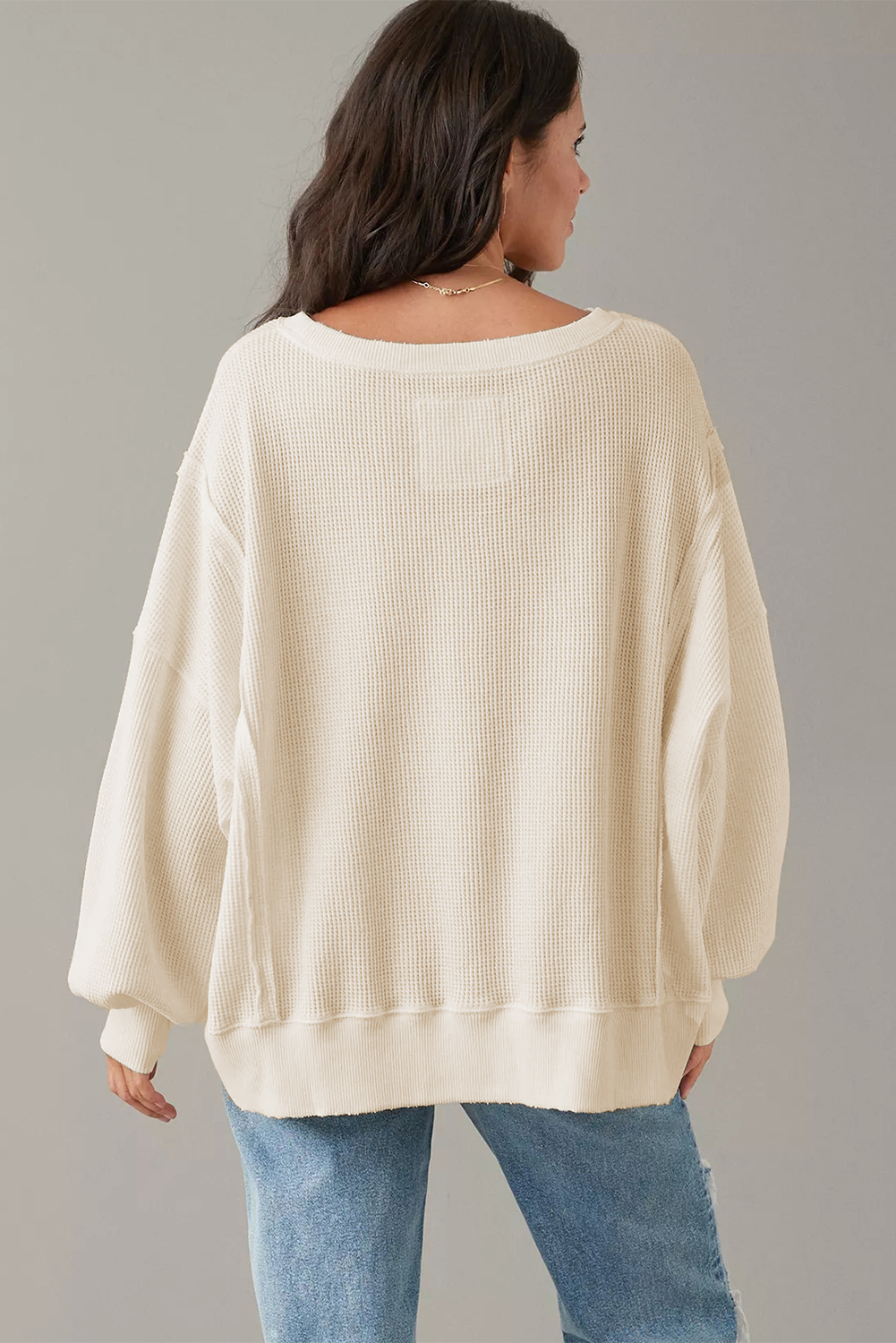 Achieve a cozy and stylish look with this Women's White Waffle Knit Bishop Sleeve Split Oversized Sweatshirt. The waffle knit construction provides both comfort and texture, making it a perfect choice for a relaxed yet on-trend silhouette. The oversized fit adds to the comfort and offers a fashionable look. Its solid white color makes it versatile and easy to style, suitable for various outfit combinations. The elegant bishop sleeves add a touch of sophistication to the sweatshirt, striking the perfect balance between chic and casual. Made from a blend of 60% cotton and 40% polyester, this sweatshirt ensures durability and breathability, ideal for the fall and autumn seasons. The round neck and split details add a modern and stylish touch to the classic sweatshirt design. Pair it with your favorite jeans or leggings for a chic and comfortable outfit. - Detail View 4 Achieve a cozy and stylish look with this Women's White Waffle Knit Bishop Sleeve Split Oversized Sweatshirt. The waffle knit construction provides both comfort and texture, making it a perfect choice for a relaxed yet on-trend silhouette. The oversized fit adds to the comfort and offers a fashionable look. Its solid white color makes it versatile and easy to style, suitable for various outfit combinations. The elegant bishop sleeves add a touch of sophistication to the sweatshirt, striking the perfect balance between chic and casual. Made from a blend of 60% cotton and 40% polyester, this sweatshirt ensures durability and breathability, ideal for the fall and autumn seasons. The round neck and split details add a modern and stylish touch to the classic sweatshirt design. Pair it with your favorite jeans or leggings for a chic and comfortable outfit. - Detail View 4