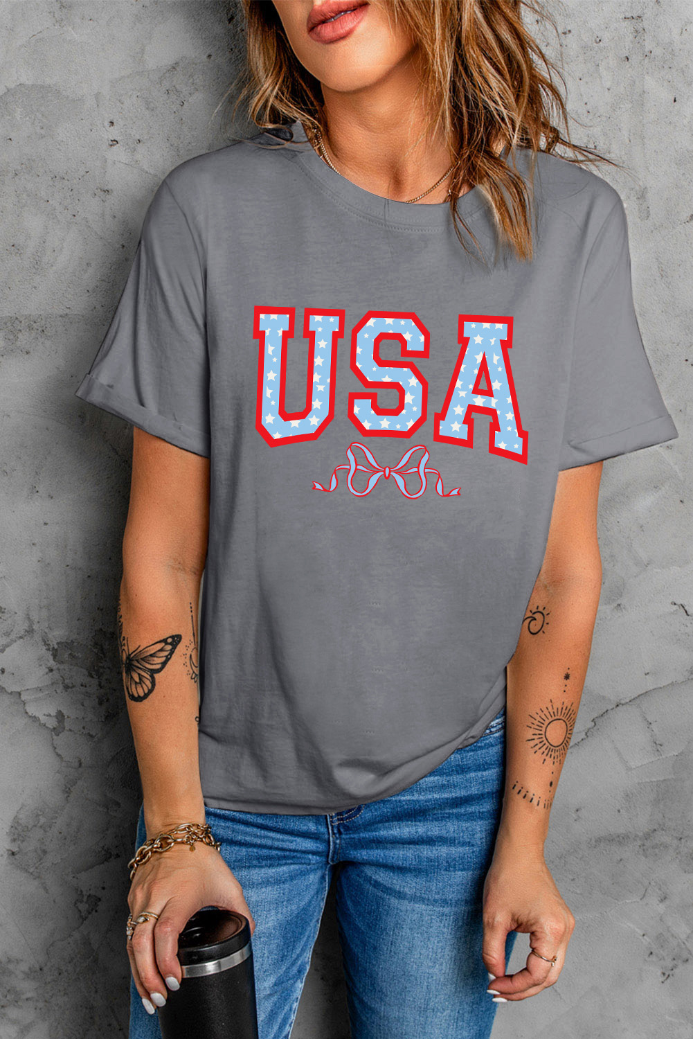Show off your USA pride and add a touch of feminine charm to your wardrobe with this Women's Gray USA Star Bow Knot Print Crew Neck T-Shirt. The bold star print is a declaration of American spirit and style, while the playful bow knot pattern adds a whimsical touch. Made from soft, durable fabric, this graphic tee offers a comfortable wear experience, perfect for casual daily wear. Pair it with your favorite jeans for a chic and effortless look. This tee is a must-have for flag-holiday enthusiasts and anyone who loves to make a statement with their fashion. - Detail View 4 Show off your USA pride and add a touch of feminine charm to your wardrobe with this Women's Gray USA Star Bow Knot Print Crew Neck T-Shirt. The bold star print is a declaration of American spirit and style, while the playful bow knot pattern adds a whimsical touch. Made from soft, durable fabric, this graphic tee offers a comfortable wear experience, perfect for casual daily wear. Pair it with your favorite jeans for a chic and effortless look. This tee is a must-have for flag-holiday enthusiasts and anyone who loves to make a statement with their fashion. - Detail View 4