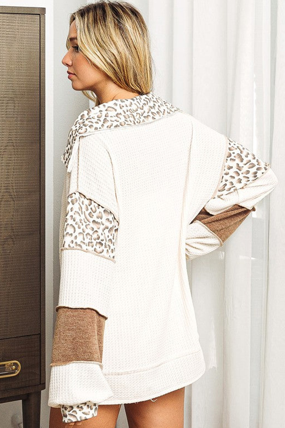 Elevate your casual style with this Women's White Leopard Patchwork Turn-down Collar Waffle Top. The chic and oversize fit of this top offers comfort and a trendy look for most body types. The leopard patchwork detail adds a touch of fashion-forward style, making it a statement piece in your wardrobe. The turn-down collar, oversize style, and tunic length give this top a modern and relaxed vibe. Featuring side slits for added detail, this pullover is perfect for the upcoming fall and autumn season. Made from premium 100% polyester, this top ensures durability and easy care. The long sleeves and V-neck collar are in line with the latest fashion trends, adding a touch of sophistication to the overall look. Pair it with your favorite jeans or leggings for a stylish and effortless ensemble. Embrace the best of fall fashion with this must-have waffle top. - Detail View 9 Elevate your casual style with this Women's White Leopard Patchwork Turn-down Collar Waffle Top. The chic and oversize fit of this top offers comfort and a trendy look for most body types. The leopard patchwork detail adds a touch of fashion-forward style, making it a statement piece in your wardrobe. The turn-down collar, oversize style, and tunic length give this top a modern and relaxed vibe. Featuring side slits for added detail, this pullover is perfect for the upcoming fall and autumn season. Made from premium 100% polyester, this top ensures durability and easy care. The long sleeves and V-neck collar are in line with the latest fashion trends, adding a touch of sophistication to the overall look. Pair it with your favorite jeans or leggings for a stylish and effortless ensemble. Embrace the best of fall fashion with this must-have waffle top. - Detail View 9