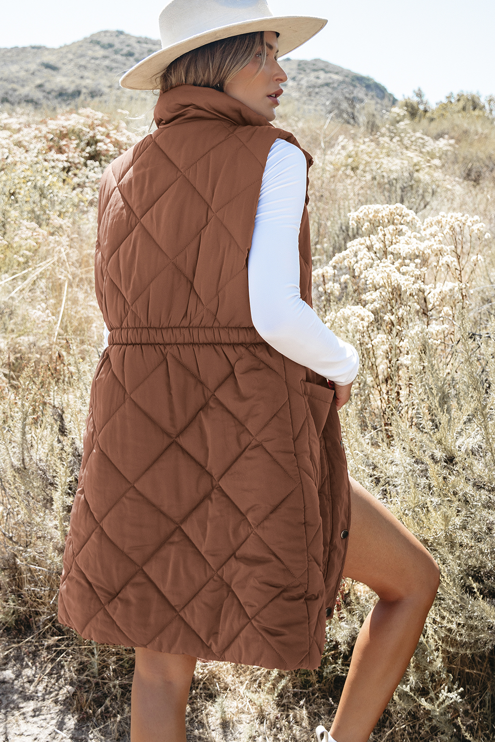 Stay warm and stylish with this Women's Coffee Quilted Longline Puffer Vest with Stand Collar. The longline coverage provides added warmth and a streamlined silhouette, while the fashionable quilted design adds a stylish texture and classic look. The stand-up collar provides extra neck protection and a sharp, chic appearance. This light and warm puffer construction is perfect for effortless layering in cold weather, making it a must-have for your winter wardrobe. The coffee brown color is versatile and easy to style, and can be paired with a variety of outfits for a chic and effortless look. - Detail View 9 Stay warm and stylish with this Women's Coffee Quilted Longline Puffer Vest with Stand Collar. The longline coverage provides added warmth and a streamlined silhouette, while the fashionable quilted design adds a stylish texture and classic look. The stand-up collar provides extra neck protection and a sharp, chic appearance. This light and warm puffer construction is perfect for effortless layering in cold weather, making it a must-have for your winter wardrobe. The coffee brown color is versatile and easy to style, and can be paired with a variety of outfits for a chic and effortless look. - Detail View 9