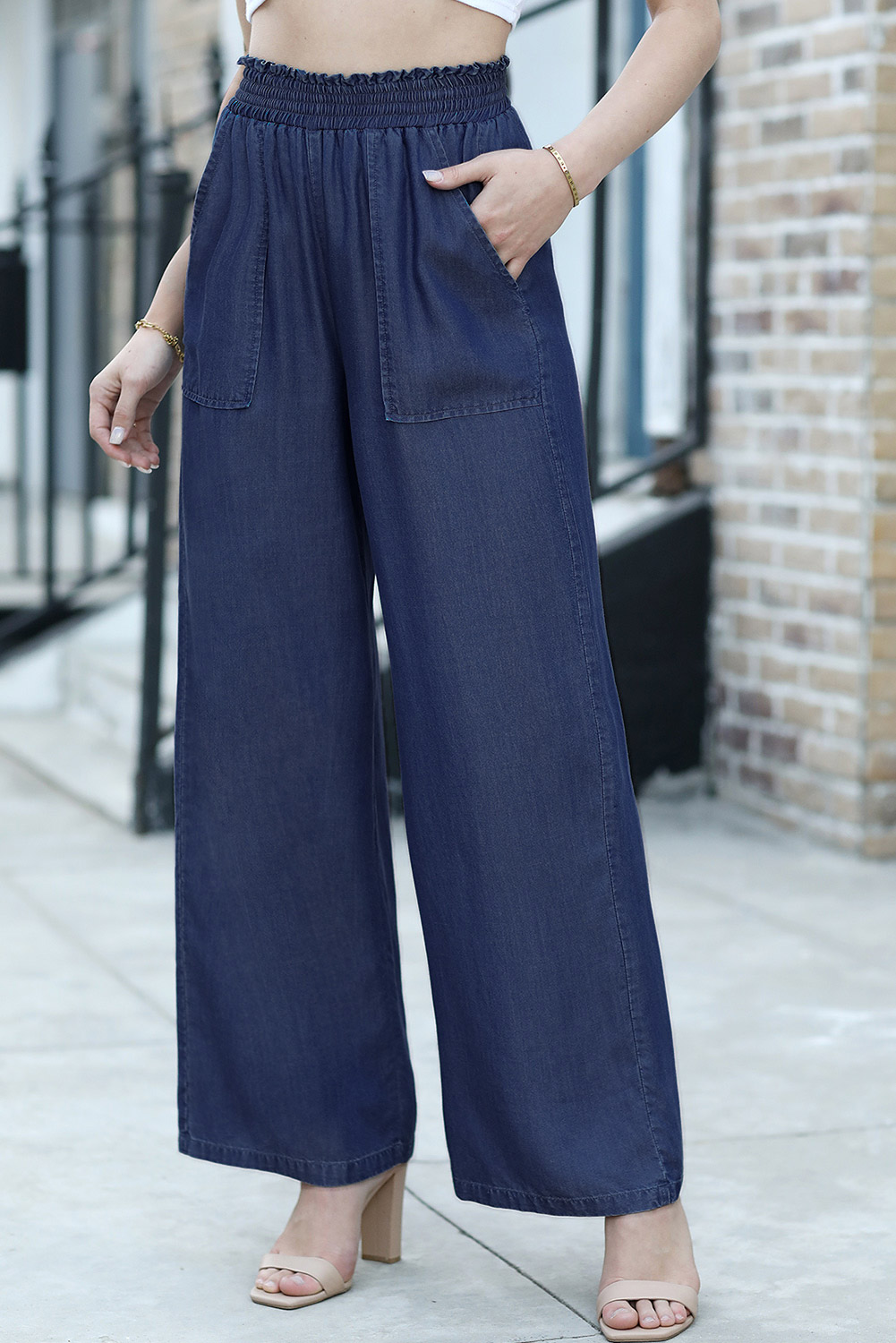 Elevate your denim collection with these Women's Sail Blue Smocked High Waist Wide Leg Jeans. The flirty ruffles and smocked high waist add feminine and eye-catching details to these stylish jeans. The trendy wide leg cut offers a modern, retro-inspired look, making them a fashion-forward choice for any wardrobe. Made from 100% lyocell, these jeans ensure breathability, softness, and lightweight comfort, perfect for all-day wear. The high waist design helps create a slim and tall silhouette, while the wide leg cut adds a touch of chic and sophistication. These women's jeans are both fashionable and comfortable, making them a versatile option for daily wear and outdoor activities. The solid sail blue color adds a pop of freshness to your outfit, ideal for the spring season. - Detail View 14 Elevate your denim collection with these Women's Sail Blue Smocked High Waist Wide Leg Jeans. The flirty ruffles and smocked high waist add feminine and eye-catching details to these stylish jeans. The trendy wide leg cut offers a modern, retro-inspired look, making them a fashion-forward choice for any wardrobe. Made from 100% lyocell, these jeans ensure breathability, softness, and lightweight comfort, perfect for all-day wear. The high waist design helps create a slim and tall silhouette, while the wide leg cut adds a touch of chic and sophistication. These women's jeans are both fashionable and comfortable, making them a versatile option for daily wear and outdoor activities. The solid sail blue color adds a pop of freshness to your outfit, ideal for the spring season. - Detail View 14