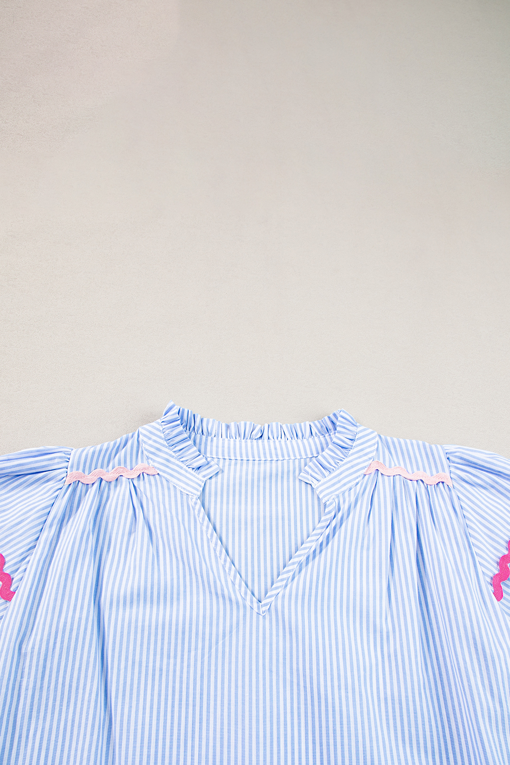 Add a touch of bohemian charm to your wardrobe with this Women's Sky Blue Stripe Ruffled Sleeve Split Neck Blouse with Ric Rac Trim. This striped blouse features intricate ric rac trim that adds a playful and whimsical flair. The split neck design creates a sophisticated and elegant look, while the ruffled sleeves create a feminine and romantic effect. Crafted from 100% cotton, this shirt is both breathable and comfortable to wear. The sky blue stripe pattern is perfect for the summer season, and its chic and casual design makes it suitable for daily wear. Pair it with jeans and sneakers for a relaxed daytime look, or dress it up with tailored pants for a more polished ensemble. This blouse is a must-have addition to your wardrobe, featuring a beautiful combination of colors and styles. - Detail View 9 Add a touch of bohemian charm to your wardrobe with this Women's Sky Blue Stripe Ruffled Sleeve Split Neck Blouse with Ric Rac Trim. This striped blouse features intricate ric rac trim that adds a playful and whimsical flair. The split neck design creates a sophisticated and elegant look, while the ruffled sleeves create a feminine and romantic effect. Crafted from 100% cotton, this shirt is both breathable and comfortable to wear. The sky blue stripe pattern is perfect for the summer season, and its chic and casual design makes it suitable for daily wear. Pair it with jeans and sneakers for a relaxed daytime look, or dress it up with tailored pants for a more polished ensemble. This blouse is a must-have addition to your wardrobe, featuring a beautiful combination of colors and styles. - Detail View 9